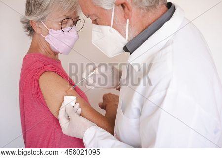 Doctor Giving Injection To Senior Caucasian Woman, Female Receiving Booster Of Covid 19 Vaccine, Peo