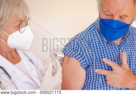 Doctor Giving Injection To Senior Caucasian Man, Old Retired Receiving Third Booster Of Covid 19 Vac