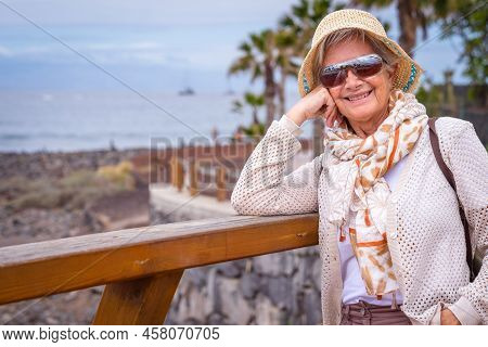 Portrait Of Happy Traveler Woman With Hat And Sunglasse Enjoying Relax In Sea Vacation Looking At Ca