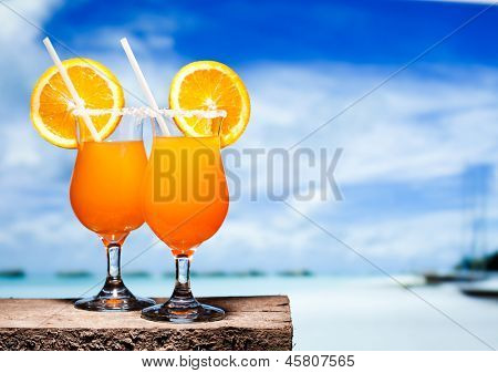 Dos tudeles de cócteles Tequila Sunrise en una mesa de playa cerca de Comentarios. Tener una pausa