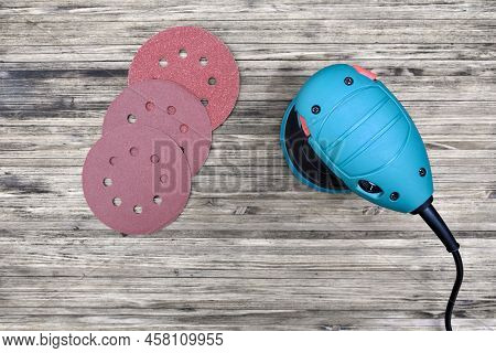 Orbital Sander Machine With Sanding Discs On Wooden Background. Adhesive Sanding Disks And Palm Sand