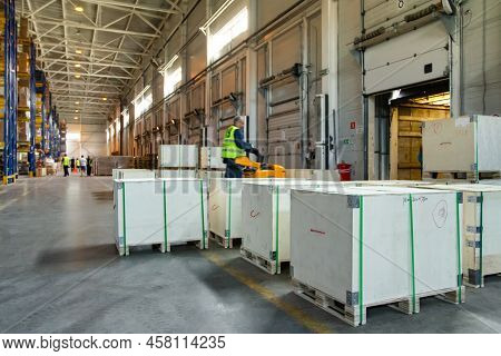Interior Of A Modern Warehouse Storage Of Retail Shop With Pallet Truck Near Shelves And Loading Ram