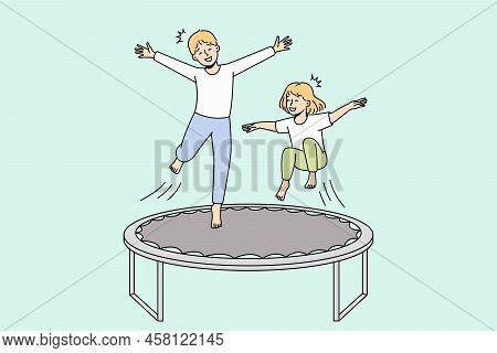 Overjoyed Small Kids Have Fun Jumping On Trampoline Outdoors. Smiling Little Children Enjoy Playing 