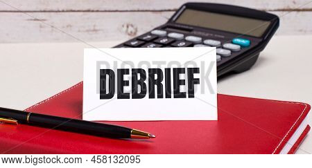 On The Office Desk There Is A Burgundy Notebook, A Calculator, A Pen And A White Card With The Text 