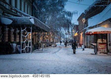 Pancevo, Serbia - December 12, 2021: Selective Blur On A Woman Walking Alone In The Snow Between The
