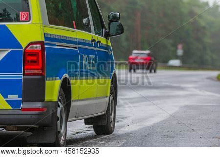 Side View Of A Police Car In An Emergency Stop Next To The Motorway. Police Vehicle In Blue And Yell
