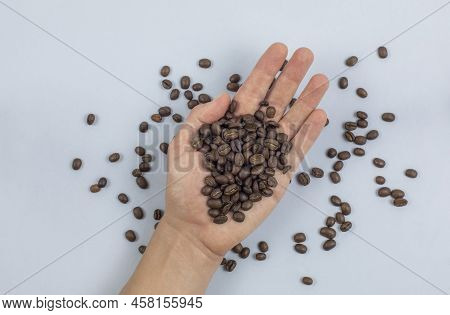 Top View Of A Hand Holding Coffee Beans Close Up With Light Blue Background