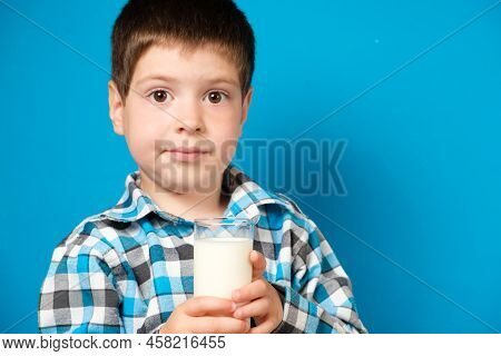A 4-year-old Boy Holds A Glass Of Milk And Squirms Looking Into The Camera. Cows Milk Protein Allerg