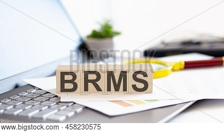 Brms - Business Rules Management System Written On A Wooden Cube On Laptop With Paper