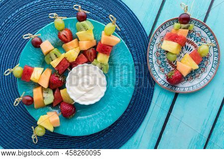Fresh Fruit Skewers On A Blue Plate Served With Yogurt Dip.