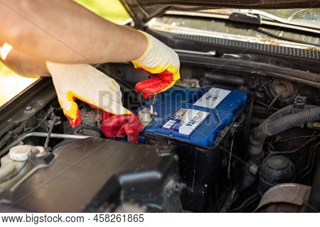 An Auto Mechanic Unscrews A Varta Car Battery Mount For Removal And Repair. Battery Replacement. Rus