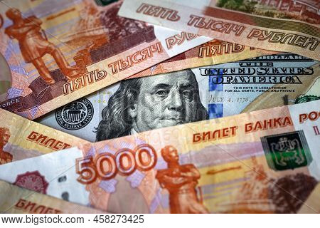 Russian Ruble Money Vs Us Dollar, Franklin From 100 Dollar Bill Watches Through Ruble Banknote Pile.