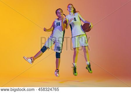Happy Girls, Basketball Players In Action Isolated On Neoned Background. Concept Of Sport, Team, Ene
