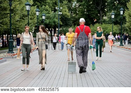 Moscow, Russia - July 2022: Worker With Broom And Dustpan Walking On A Street In Crowd Of People. Ja