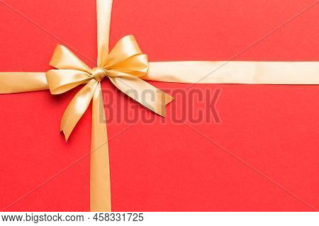 Top View Of Gold Ribbon Rolled And Yellowbow Isolated On Colored Background. Flat Lay With Copy Spac
