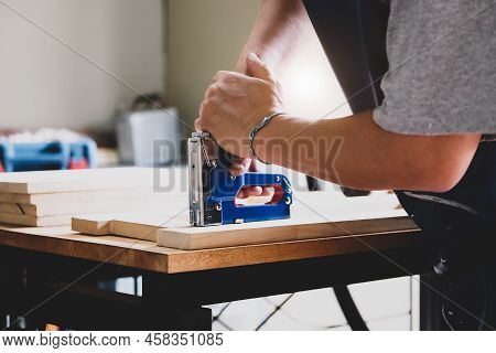 Entrepreneur Woodwork Holding A Tacker To Assemble The Wood Pieces As The Customer Ordered