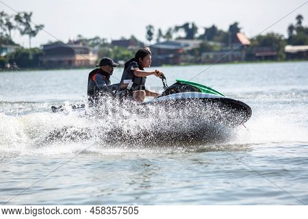 Asian Teenager On Jet Ski With Trainer. Teen Age Boy Skiing On Wave Runner. Young Man On Personal Wa