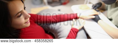 Top View Of Young Female Sitting On Appointment In Beauty Studio And Enjoy Getting Her Nails Done. N
