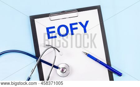 On A Blue Background, A Stethoscope, A Pen And A Tablet With Paper And The Text Eofy. Medical Concep