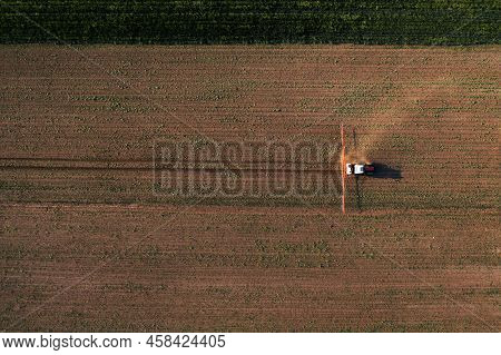 Aerial Shot Of Agricultural Tractor With Crop Sprayer Attached Spraying Herbicide Chemical Over Corn