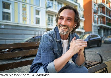 Smiling Positive Emotion Middle Aged Man Leaned His Hands On Knee Looking Sideways Sitting At The Be