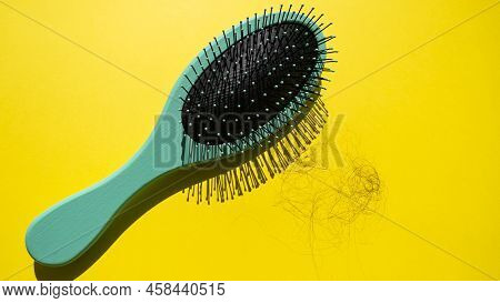 Green Comb And Fallen Hair On The Yellow Background. Baldness And Hair Loss Problem