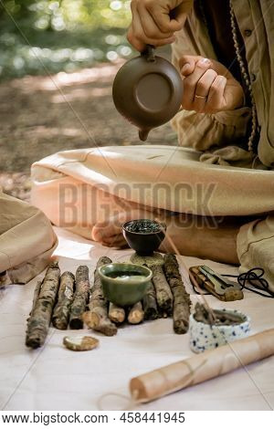 Cropped View Of Man Pouring Tea In Bowl Near Vargan On Blanket In Forest