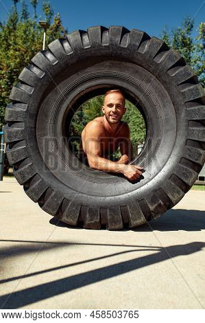 Strong Man Training Workout Lifting Large Tire Outdoor Gym. Sportive Young Adult Caucasian Guy Flip 