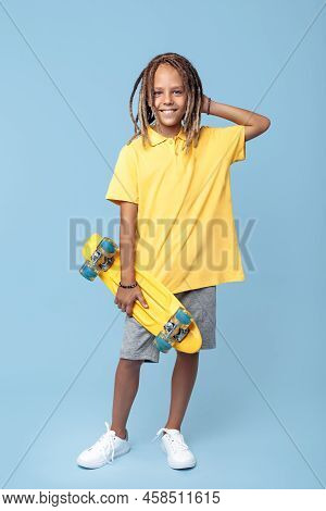 Cheerful Little Boy With African Dreads With Skateboard On The Blue Background.