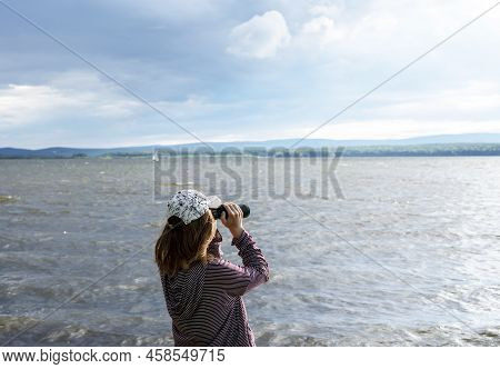 Young Woman In Cap Looking Through Binoculars At Birds On The Lake Or River Birdwatching, Zoology, E
