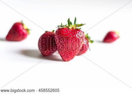 Three Strawberries Close-up On A Light Background. Main Strawberrie In Fosus And Others In The Backg