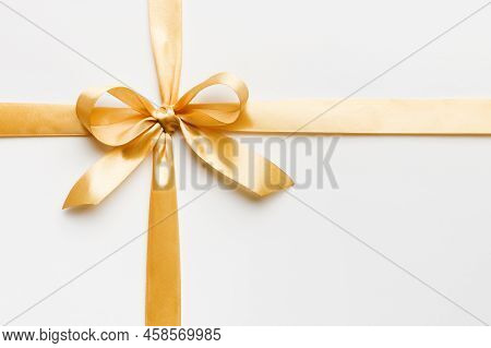 Top View Of Gold Ribbon Rolled And Yellowbow Isolated On Colored Background. Flat Lay With Copy Spac