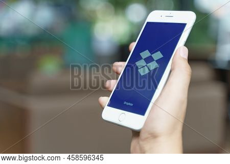 Chiang Mai, Thailand - Jul. 11,2021: Man Holding Apple Iphone With Dropbox On Screen With Blur Backg