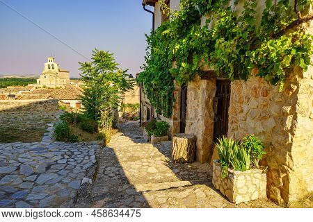 Nice Alley With Old Stone Houses And Romanesque Church In The Background In San Esteban De Gormaz, S