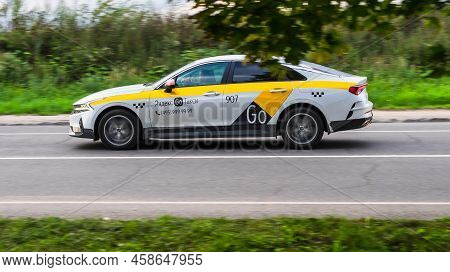 Moscow, Russia - August 2021: City Taxi Yandex Car Rushes Down A Rural Road. Yellow And White Sedan 
