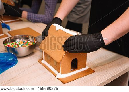 The Process Of Making A Gingerbread House, Gluing The Ginger Roof With Icing, Squeezing Tight