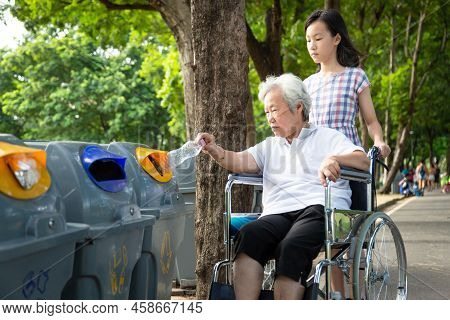 Asian Little Child Girl Or Granddaughter And Senior Grandmother Hand Putting Plastic Water Bottle In
