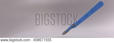Medical Scalpel With Blue Handle On Gray Background.
