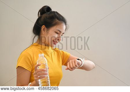 Sporty Young Woman Drinking Water And Checking Fitness Results On Her Smartwatch During Exercising A