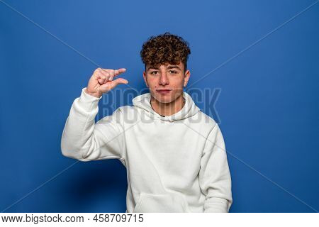Unhappy Young Man Looking Disappointed And Showing A Small Gesture, A Small Amount Or A Downscale Si