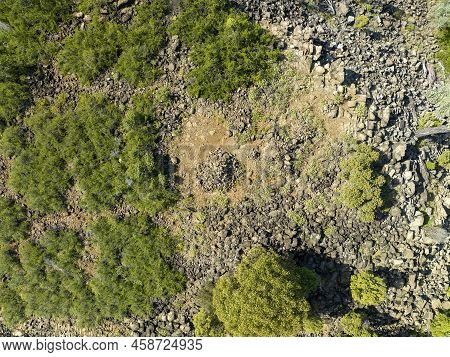 Drone Aerial Down Onto A Pile Of Rocks On Top Of A Stoney Mountain Amongst Bushland.