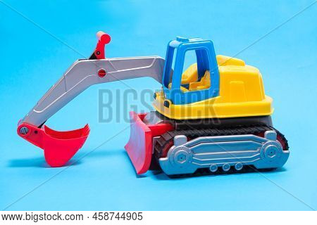 Yellow Excavator Plastic Car On Blue Background. Construction Machinery Car For Digging For Toy Stor