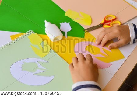 A Small Child Makes Paper Crafts For Mother's Day Or Birthday. A Boy Makes Paper Flowers For Mom. A 