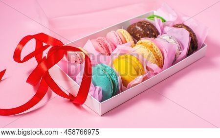Colorful Sweet Macarons Or Macaroons, Flavored Cookies Are In The Paper Box On The Pink Background