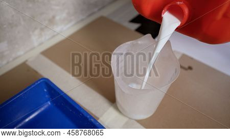 Tray Of Paint With Primer. A Worker Pours Primer Into A Measuring Cup. Preparation For Painting Work