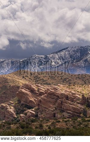 Several Layers In One Photo.  Storm Clouds Over Snowy Mountains With Vasquez Rocks In The Foreground