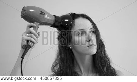 A Woman With Curly Hair Dries Her Hair With A Hair Dryer With A Diffuser Attachment. Black And White