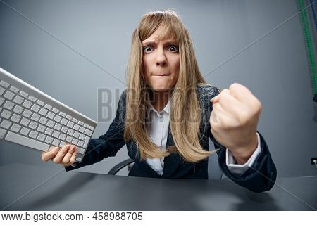 Crazy Angry Millennial Blonde Businesswoman Worker In Blue Jacket Throws Keyboard And Threatens At C