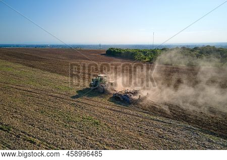 Aerial View Of Tractor Plowing Agriculural Farm Field Preparing Soil For Seeding In Summer