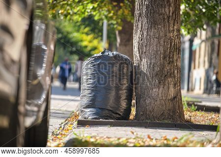 Pile Of Black Garbage Bags Full Of Litter Left For Pick Up On Street Side. Trash Disposal Concept